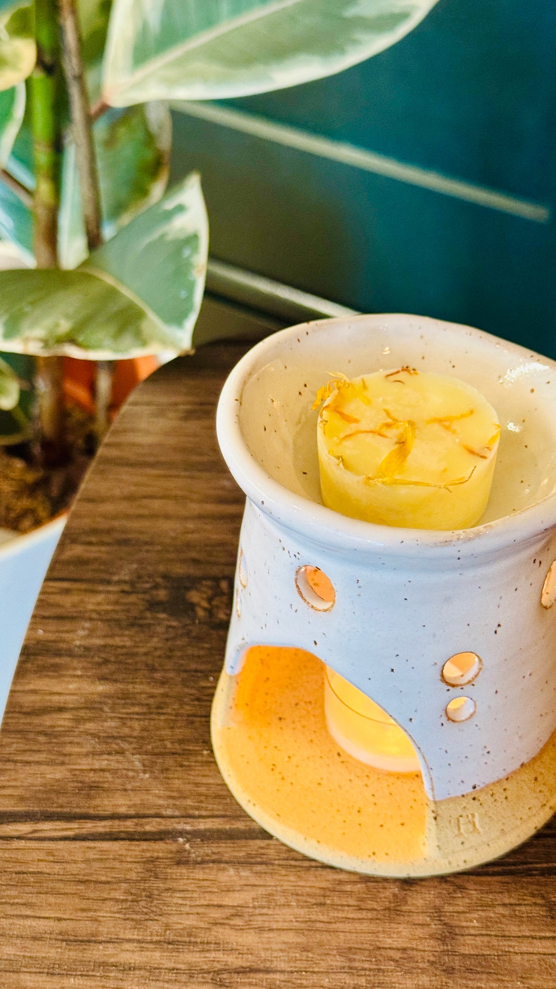 essential oil mandarin & Marjoram wax melts with the burner behind on a wooden table
