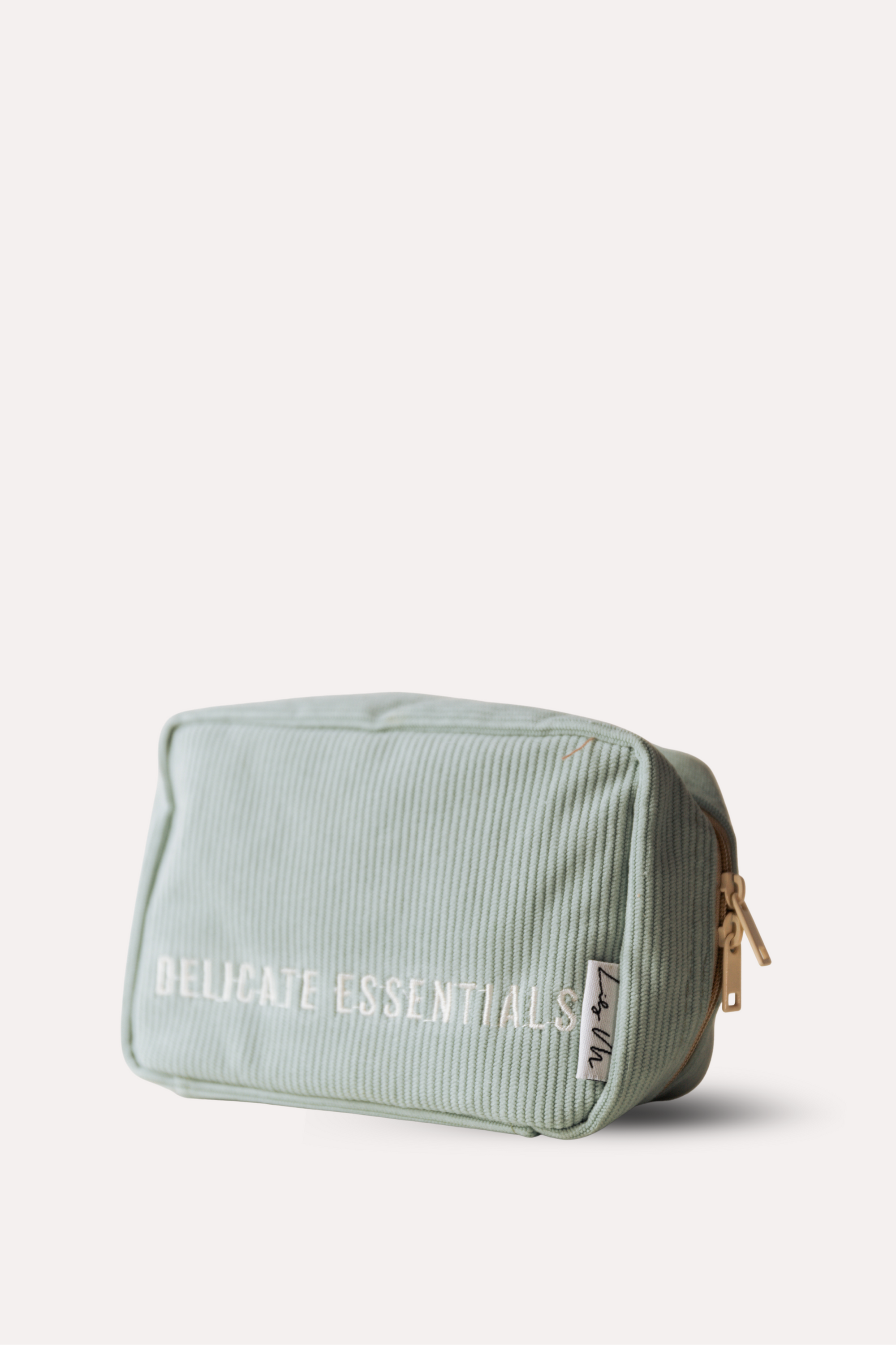 Light green toiletry bag with 'Delicate Essentials' text on a white background