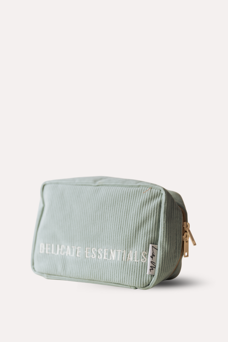 Light green toiletry bag with 'Delicate Essentials' text on a white background
