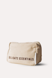 Beige toiletry bag with 'Delicate Essentials' text on a white background