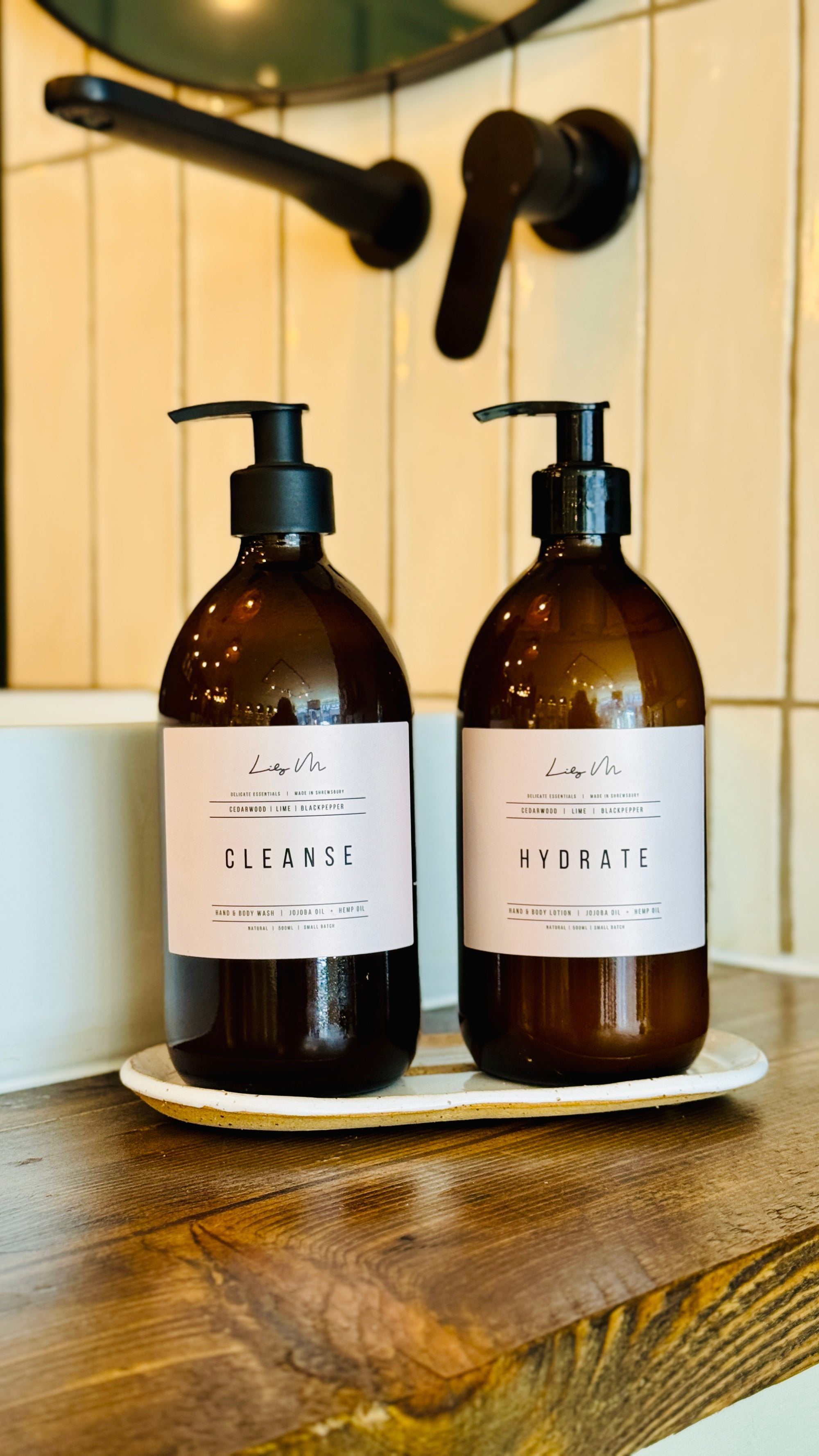 Cedarwood lime & Black pepper hand & Body lotion and Hand & Body wash together on a handmade stoneware bottle holder tray 