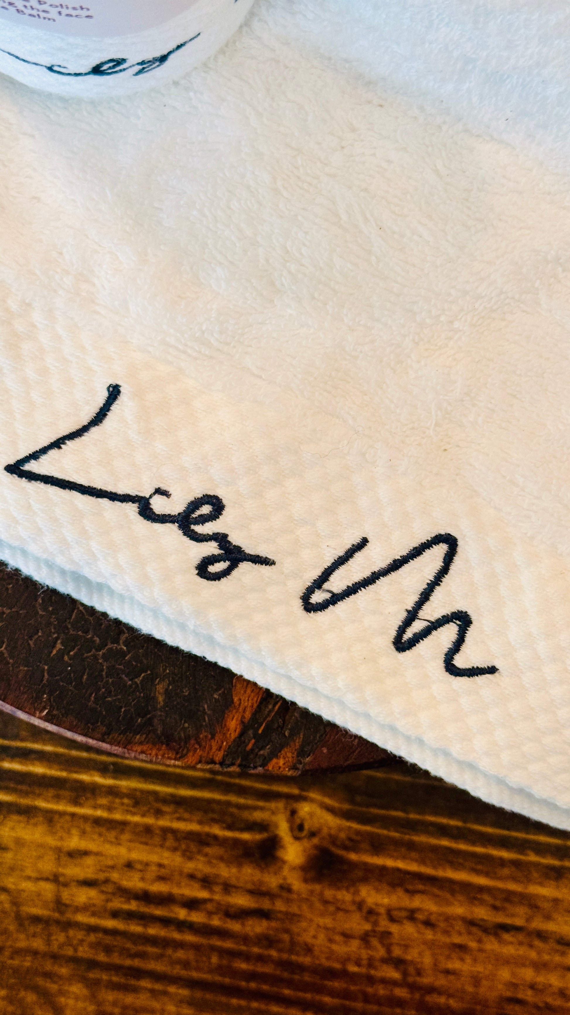 Close-up of the Lily M logo on the branded towel with dark green embroidery 