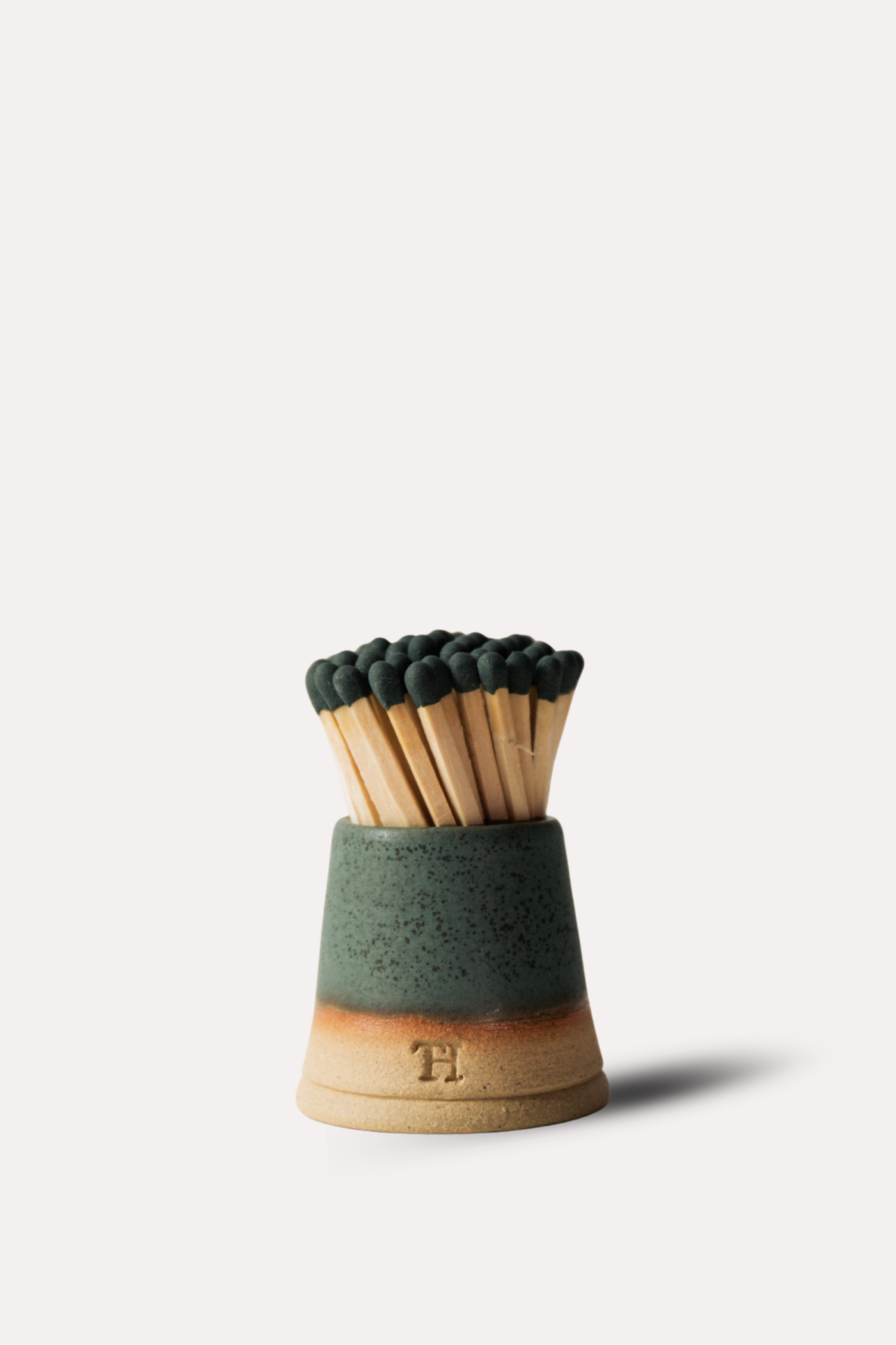 Matches in a green and wooden holder on a white background