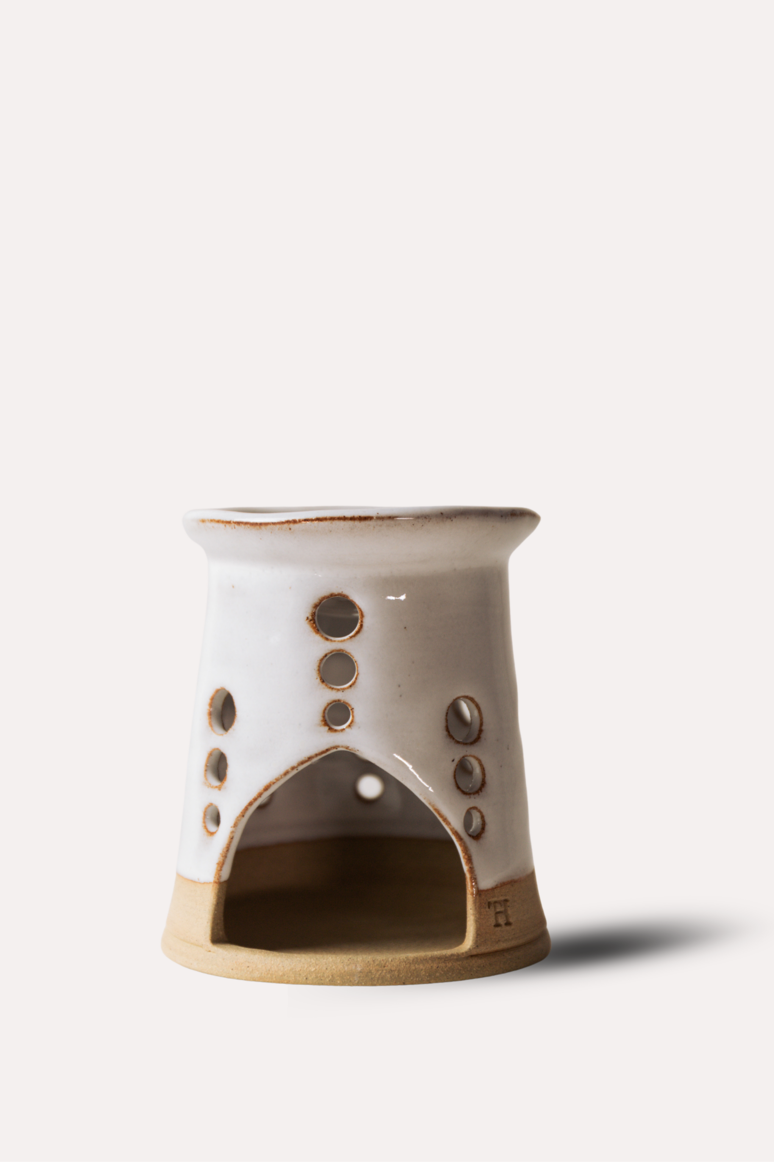 Ceramic oil burner with circular holes on a white background