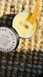 multi purpose balm with lid off and a wooden Lily M spatula, showing the texture - image rotated slightly to see more of the lid
