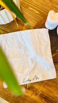 Lily M Branded face towel with an leaf in the foreground 