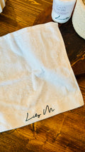 Lily M branded face towel opened up t see size and texture of the Terry material