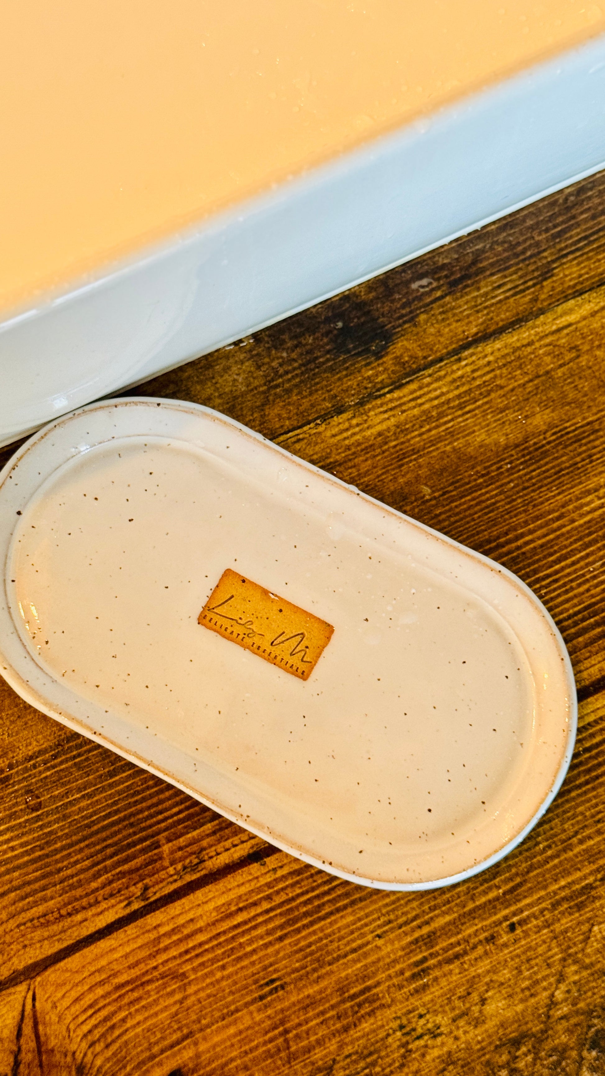 hand wash bottle tray on a wooden table  Lily M logo stamped in the center of the tray unglazed, shows a brown rectangle around the logo