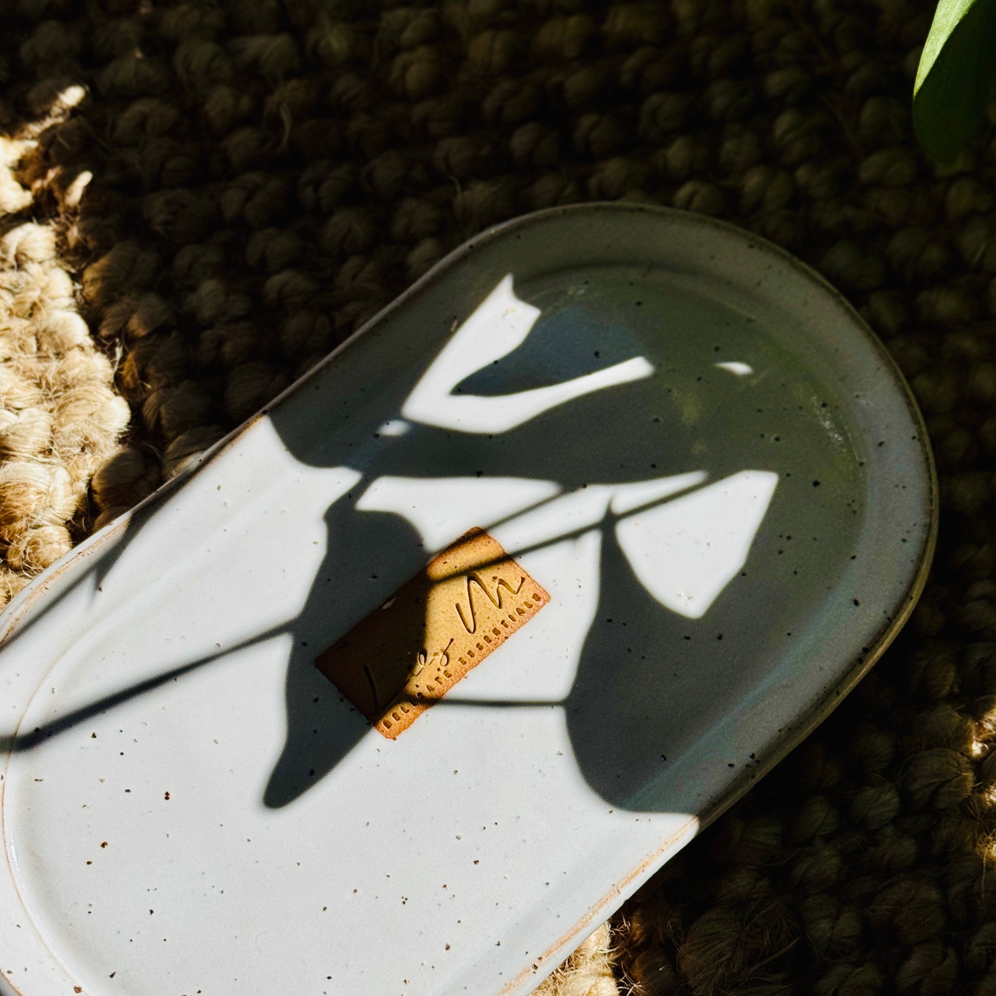 hand wash bottle tray on a hessian rug with a plant shadow covering it, Lily M logo stamped in the the center of the tray 