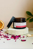 Jar of deodorant balm on a white stand with an orange and dried flowers on a beige background